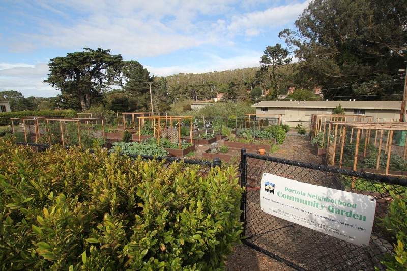 a community garden with a sign and a fence