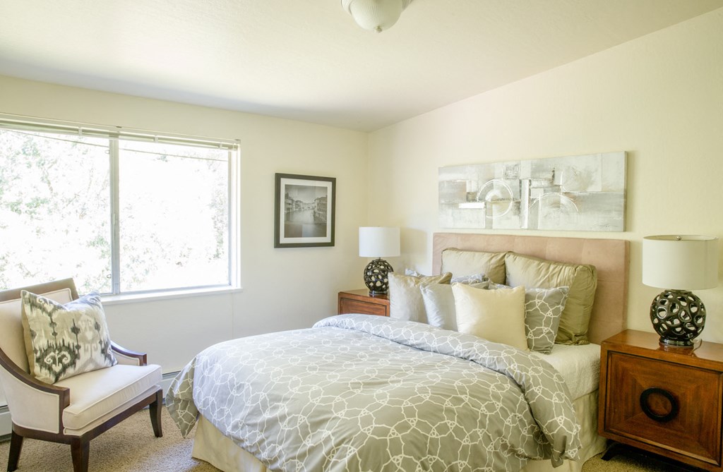 a bedroom with a bed and a chair and a window