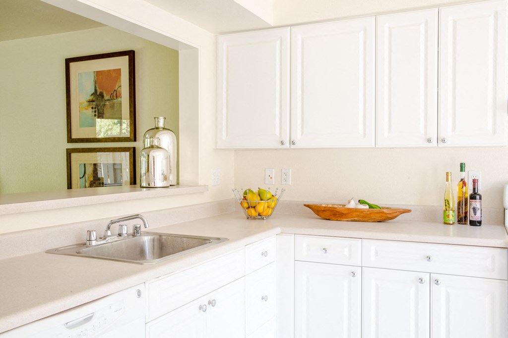 a white kitchen with white cabinets and a sink