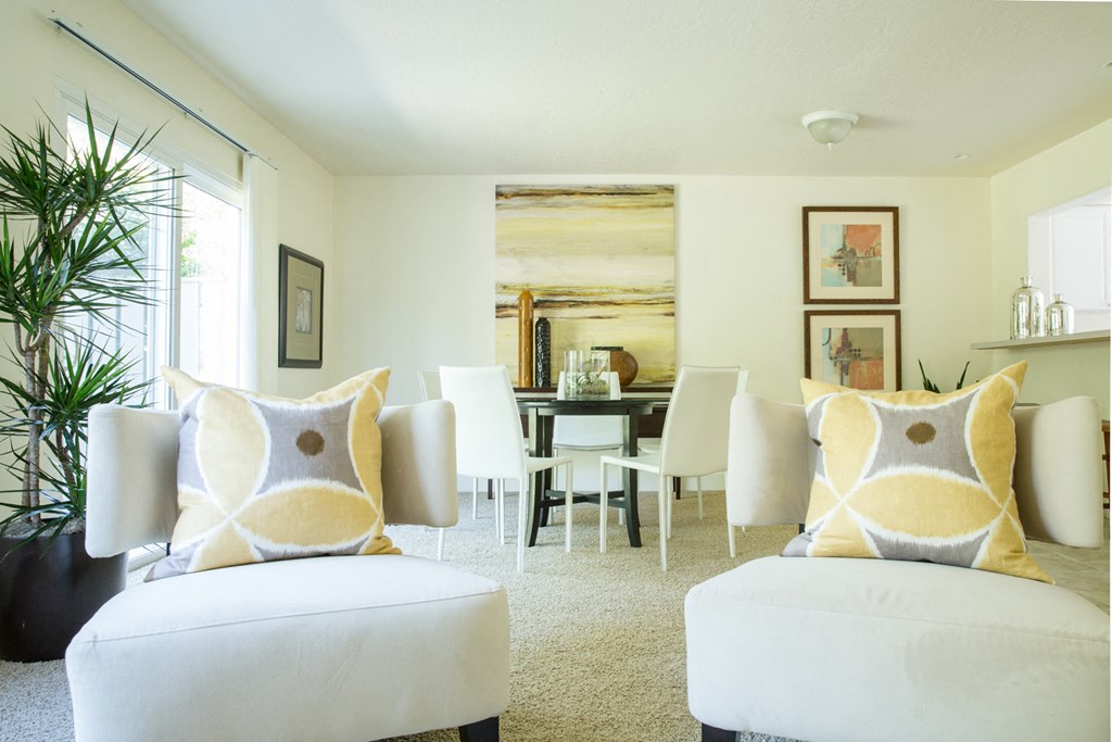 a living room with white chairs and a dining room table