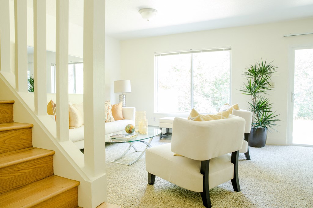 a living room with white furniture and a staircase