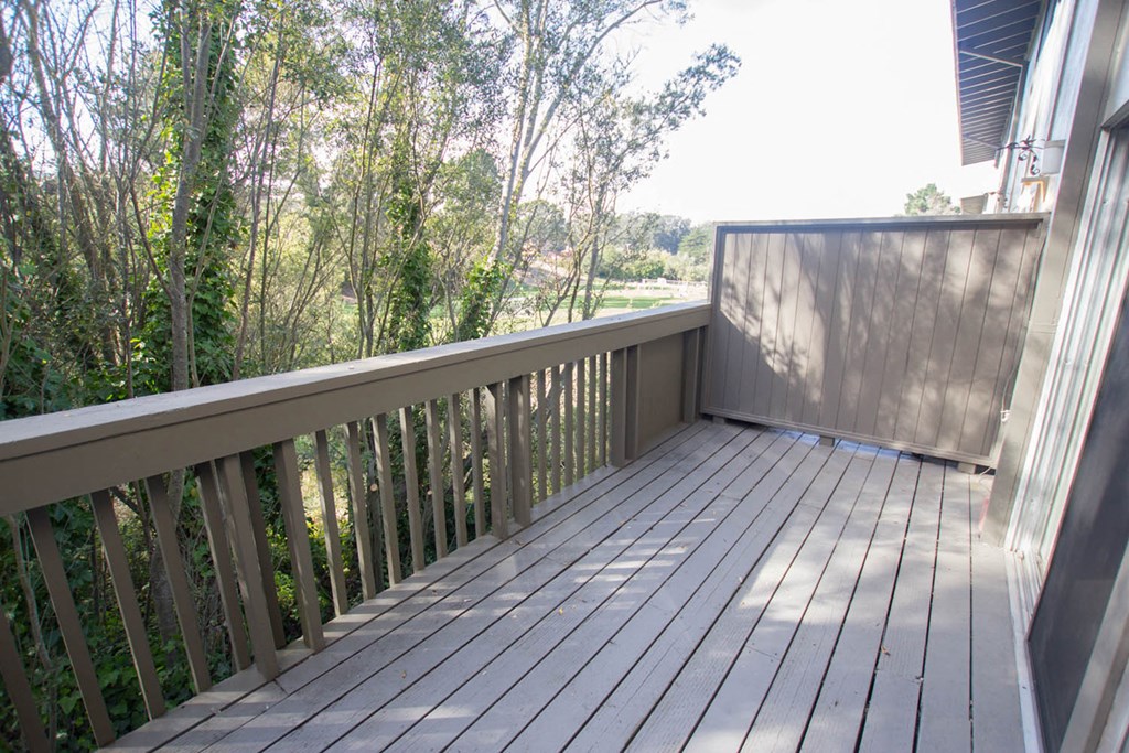 a deck with a view of trees and a body of water
