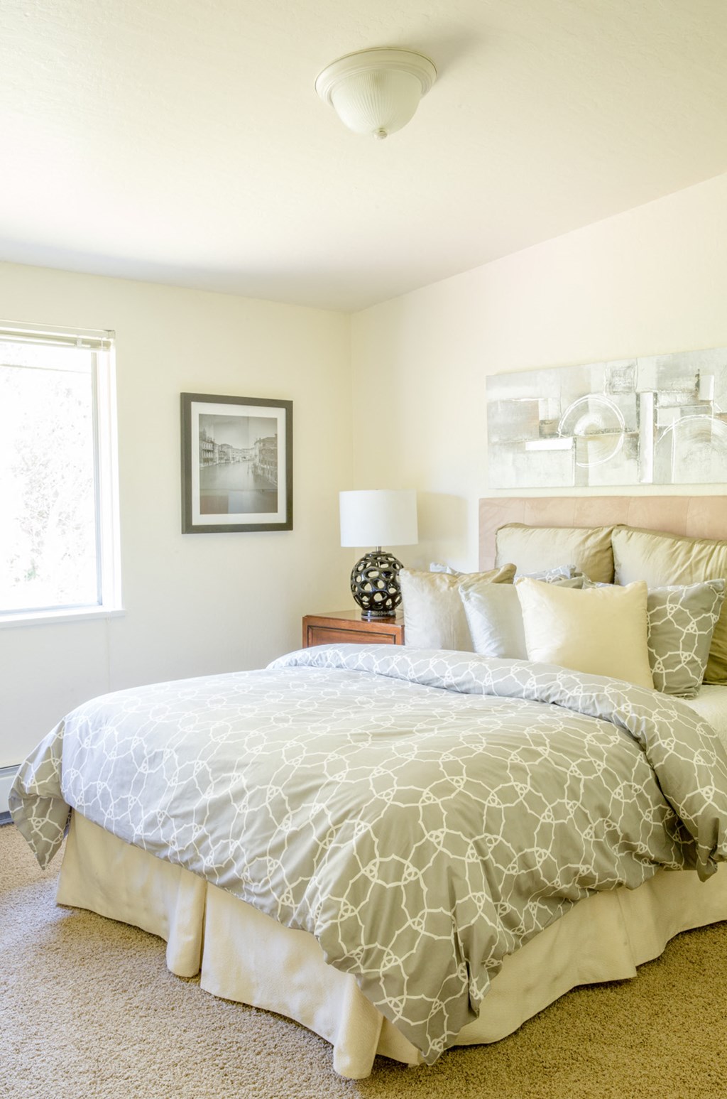 a bedroom with a bed with a white comforter and pillows