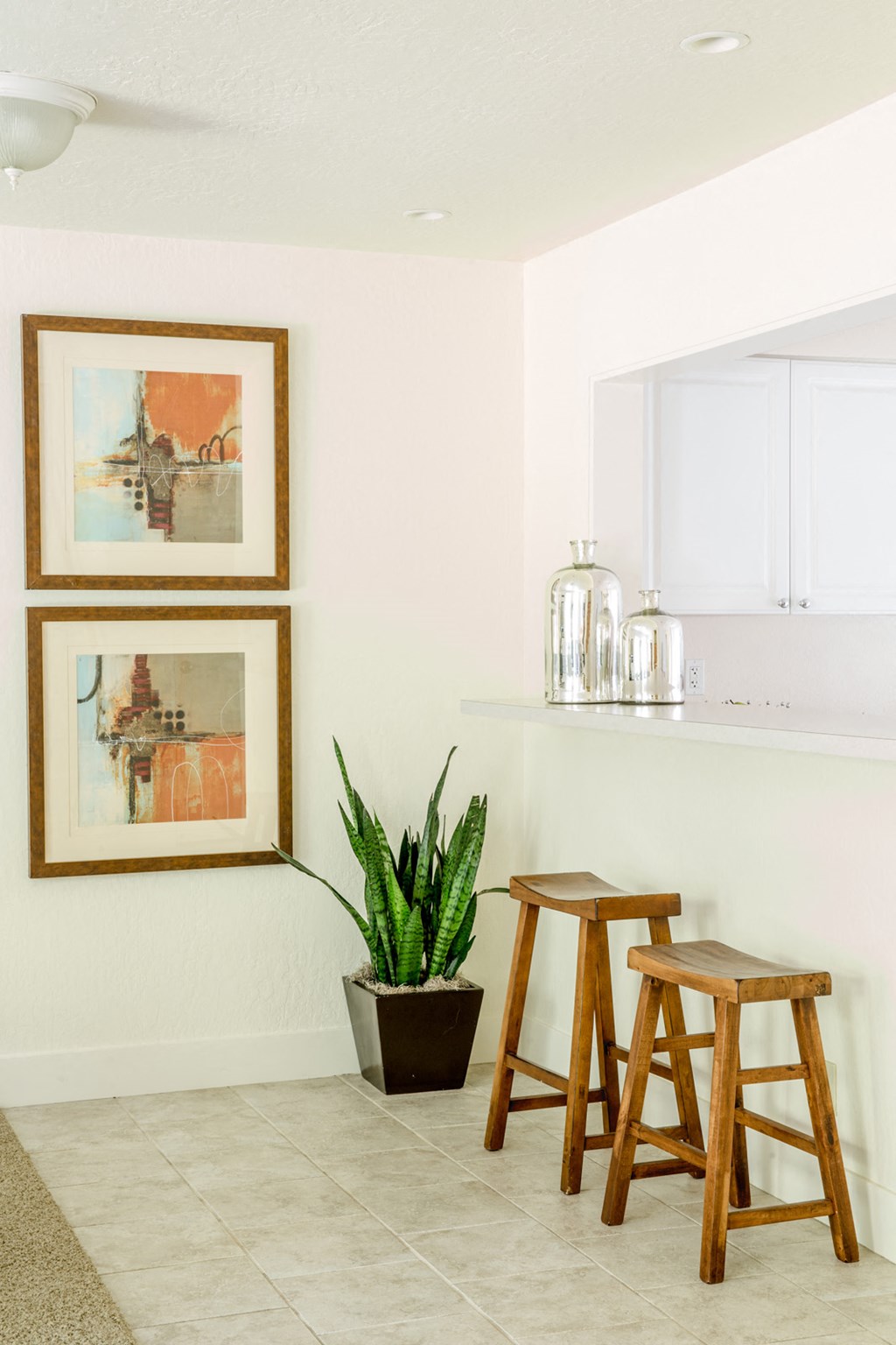 three wooden stools in a kitchen with a plant and pictures on the wall