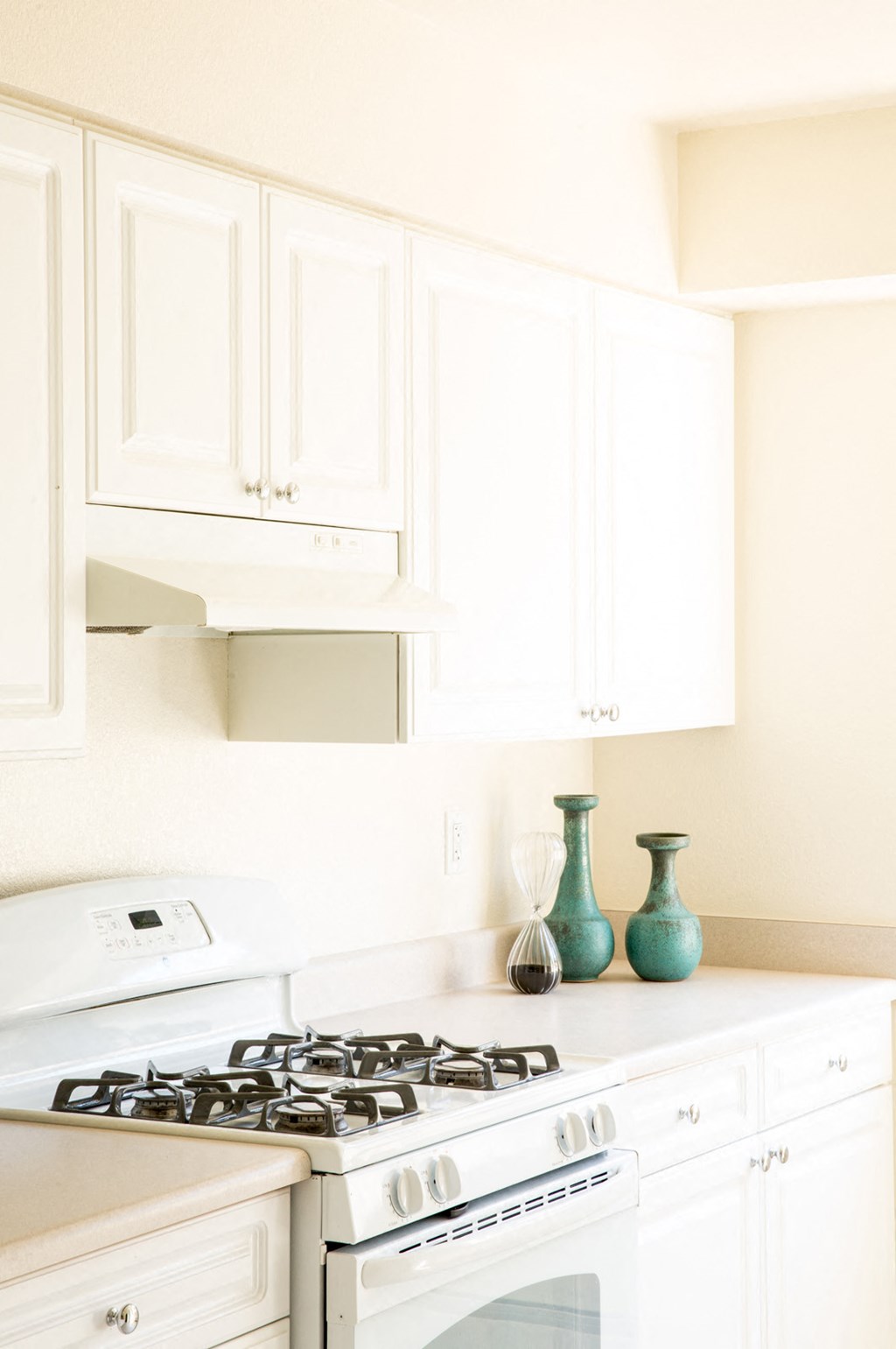 a white kitchen with a stove and white cabinets