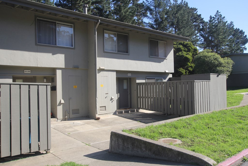 the front of a house with a fence and a sidewalk