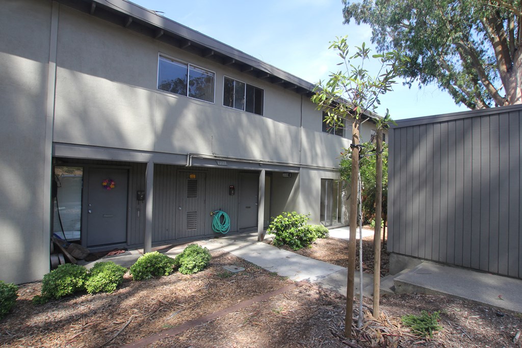 the exterior of a gray building with a driveway and trees
