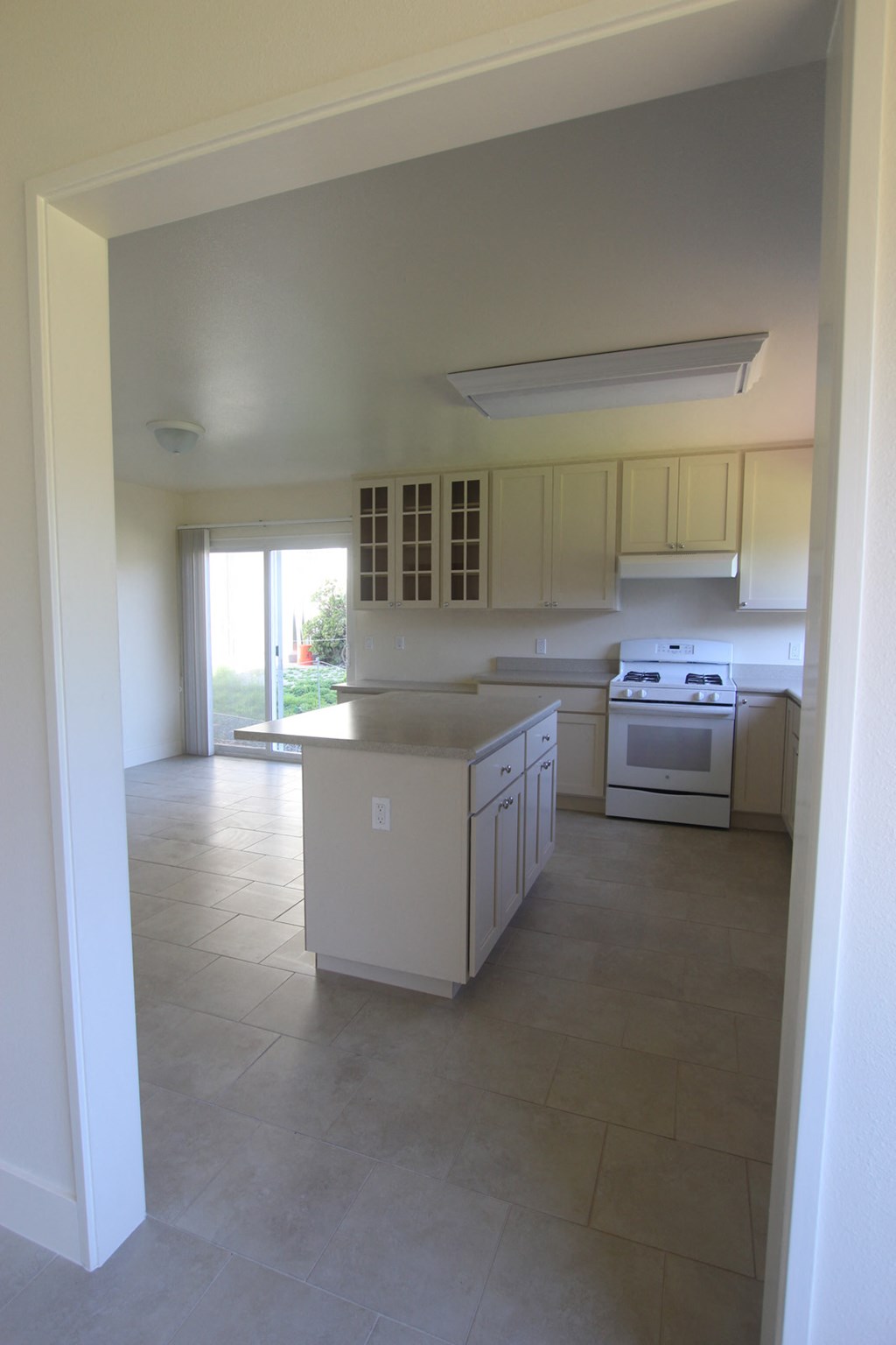 an empty kitchen with white cabinets and a white counter top