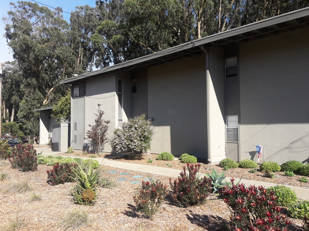 a gray house with a garden in front of it