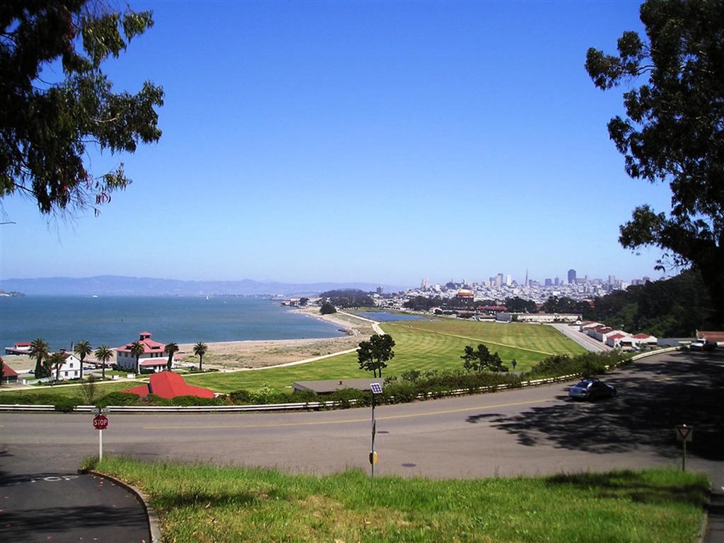 a view of the city and the beach from the top of a hill