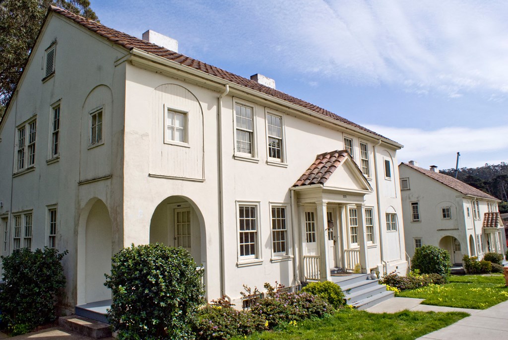the front of a white house with a sidewalk and grass