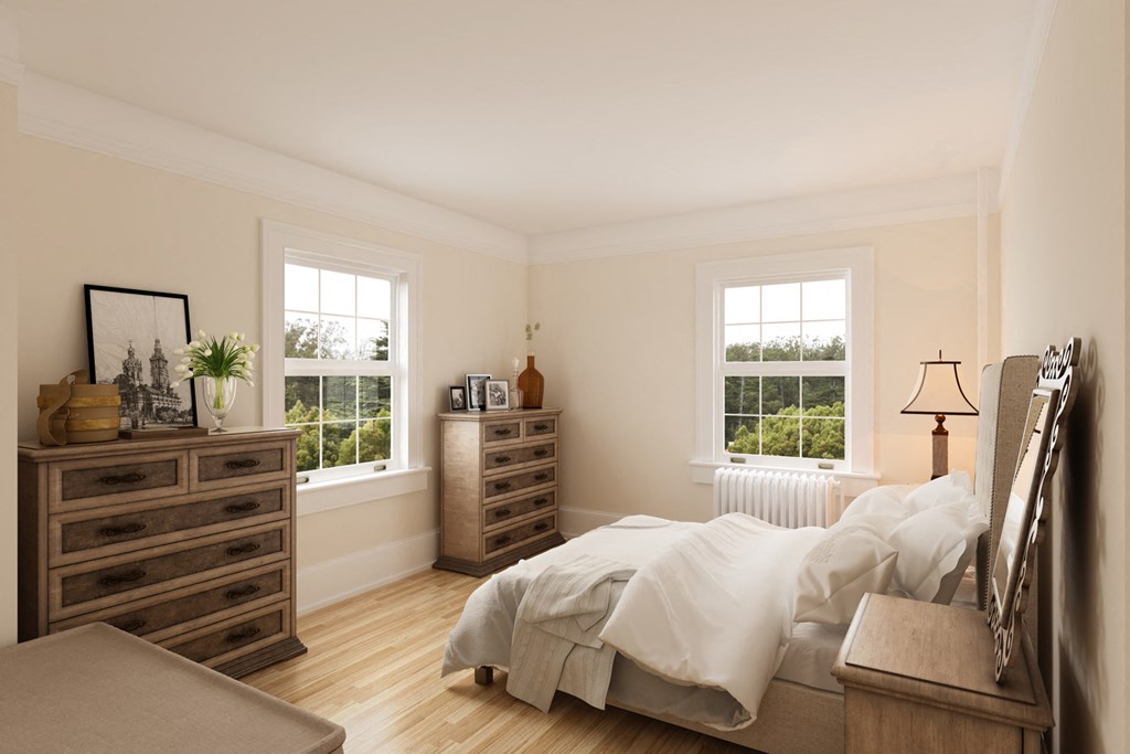 a bedroom with a bed and dressers and two windows