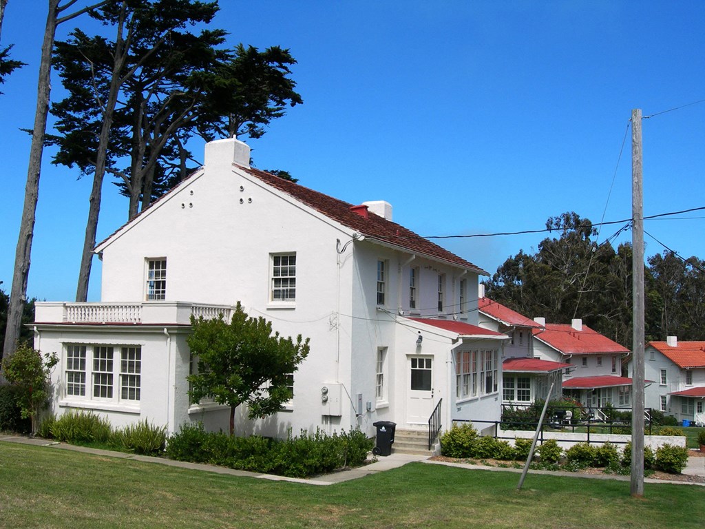 a white house with a red roof in front of some houses