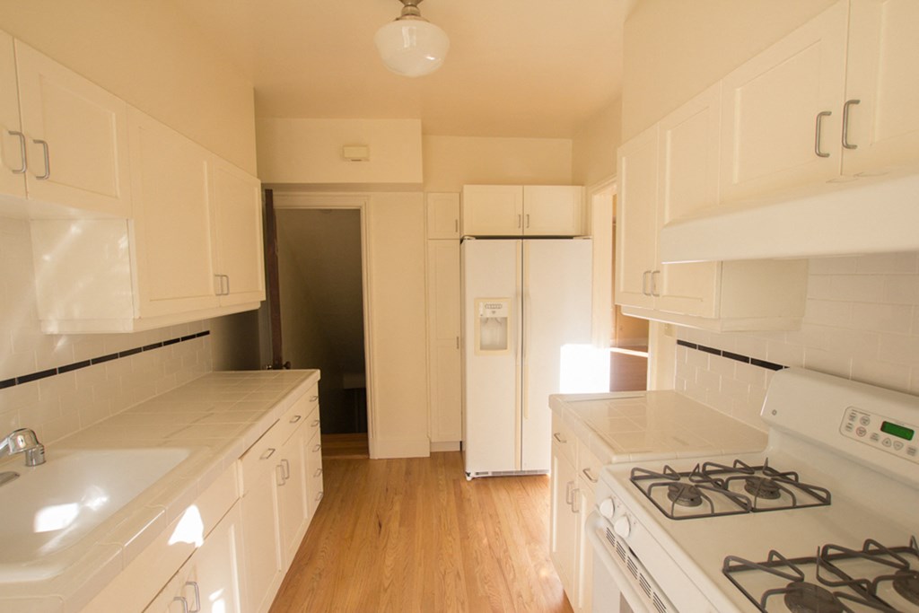 an empty kitchen with white appliances and white cabinets