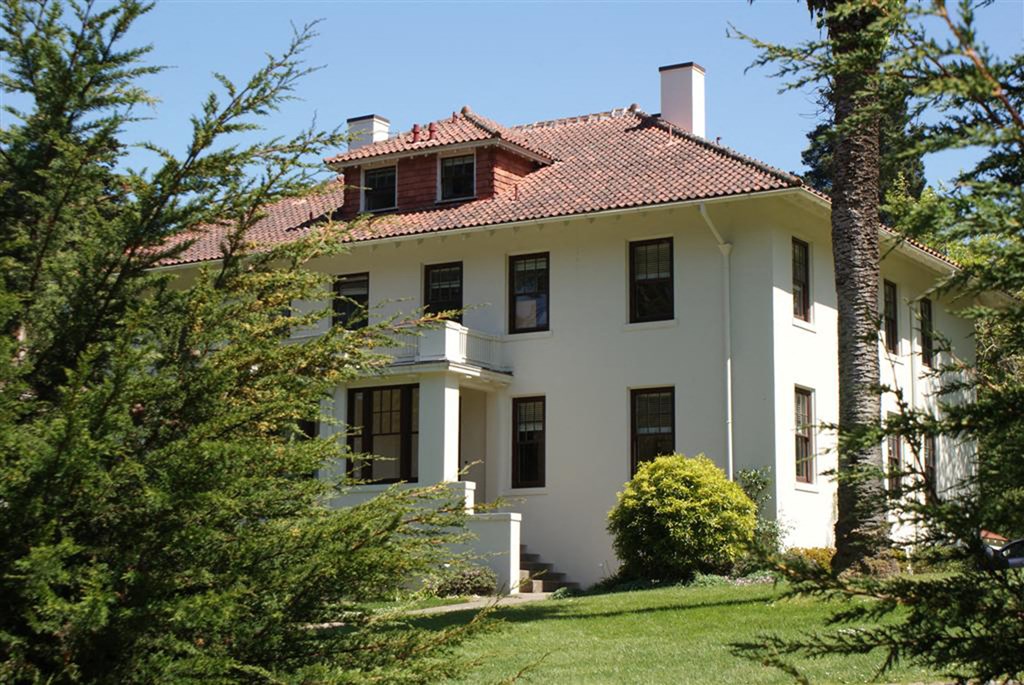 a white house with a red roof and trees