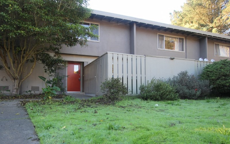 the front of a house with a yard and a red door