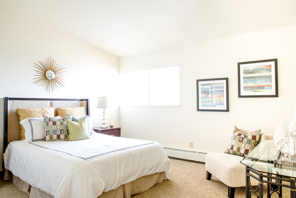 a bedroom with a bed and a chair and a table