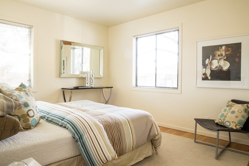 a bedroom with a bed and two windows