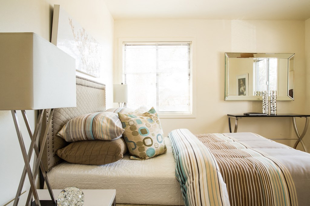 a bedroom with a bed with pillows and a mirror