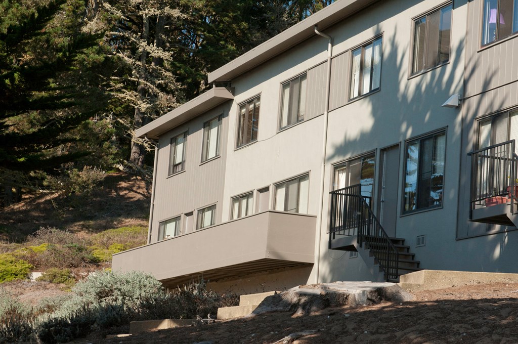 the side of a building with a staircase and trees