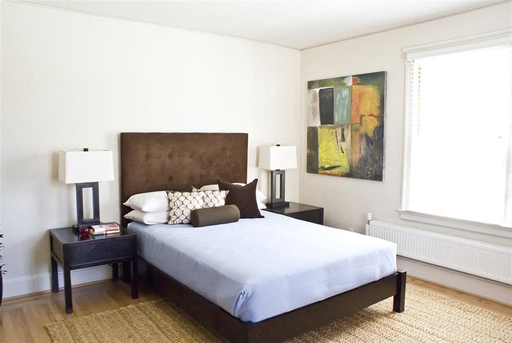 a bedroom with a bed and a painting on the wall