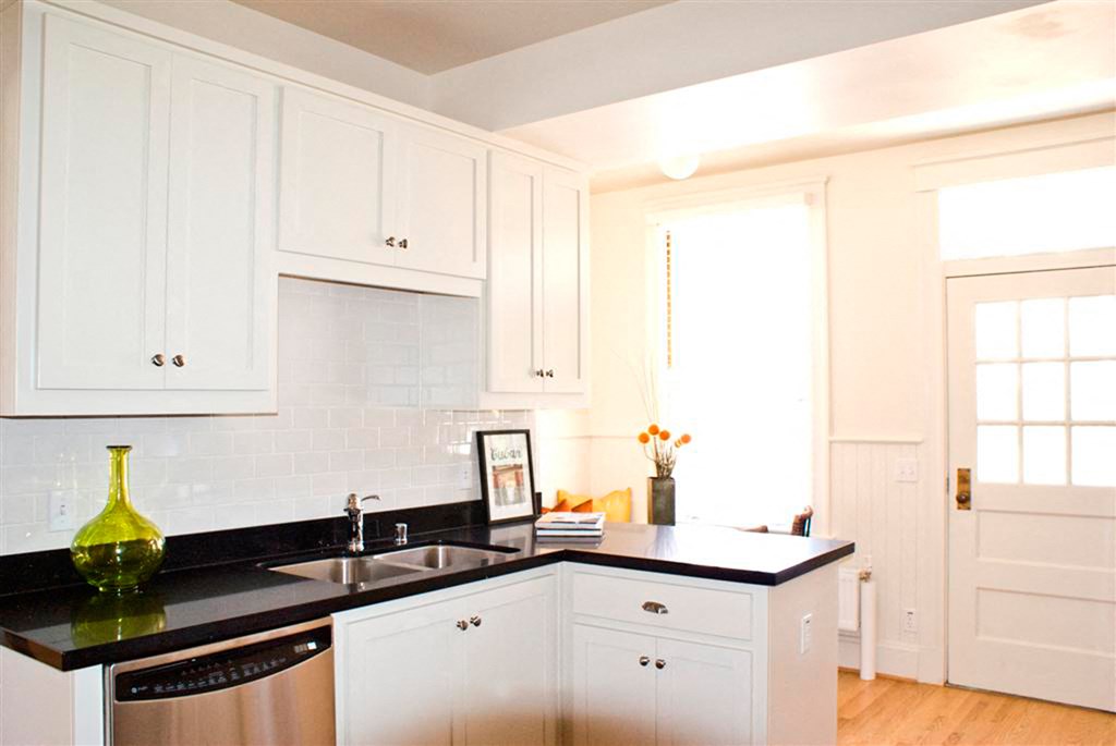 a white kitchen with black counter tops and white cabinets