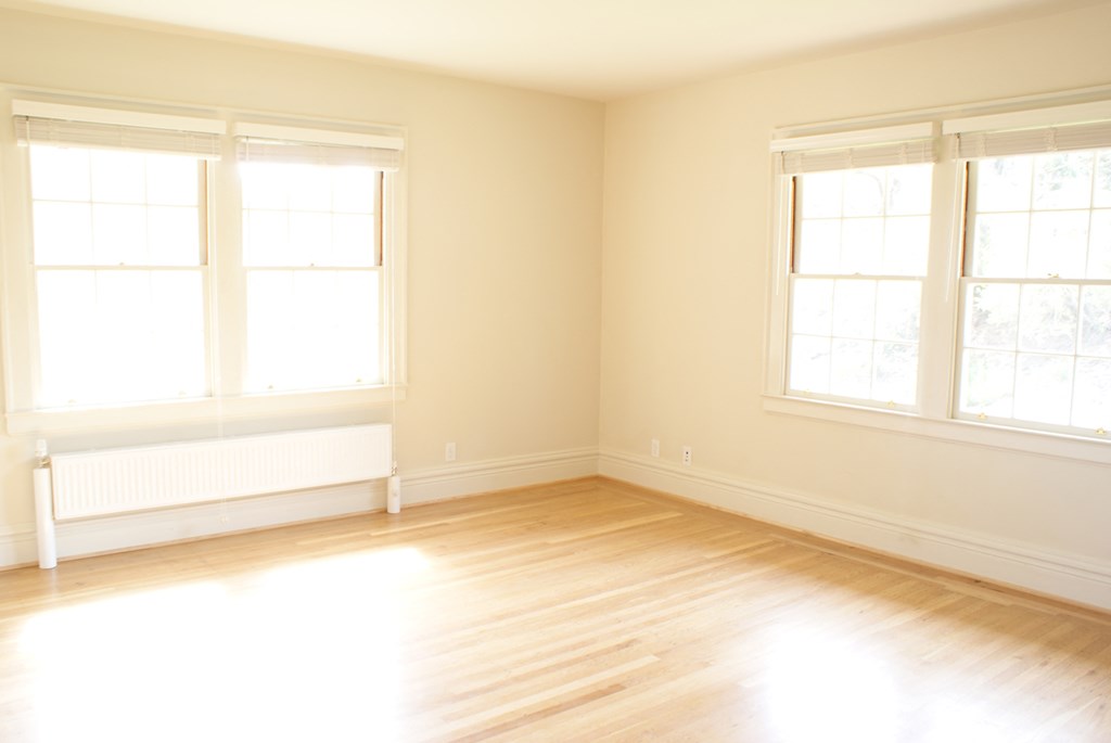 an empty room with three windows and a wooden floor