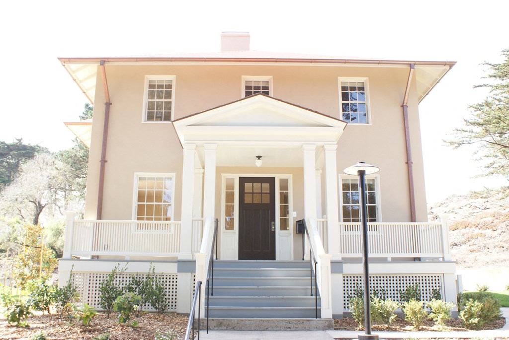 the front of a pink house with stairs and a black door