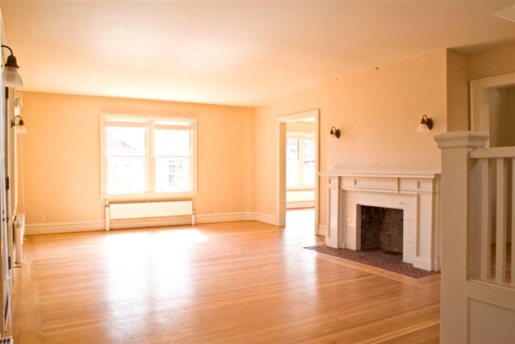 an empty living room with a fireplace and wooden floors