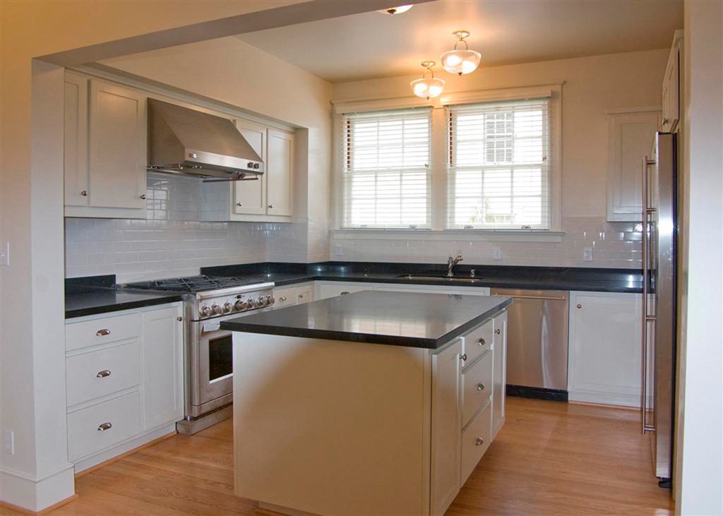 a kitchen with white cabinets and a black counter top