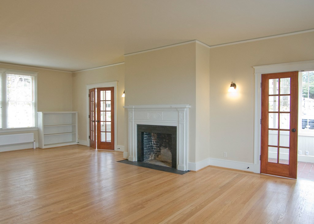an empty living room with a fireplace and a wooden floor