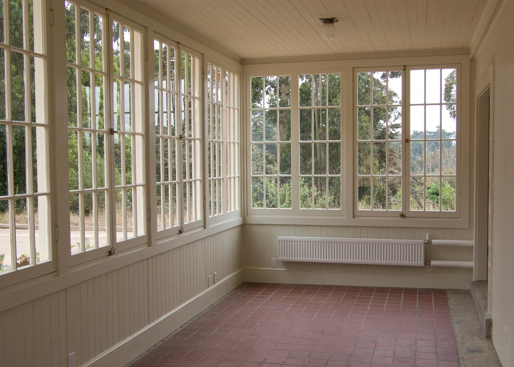 a sun room with large windows and a red brick floor