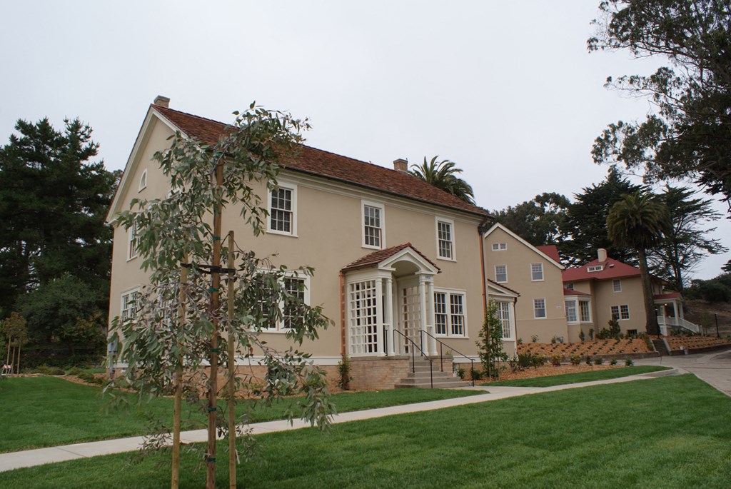 a yellow house with a green lawn and trees in front of it