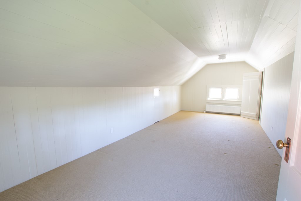 the living room of an empty attic with white walls and a white door