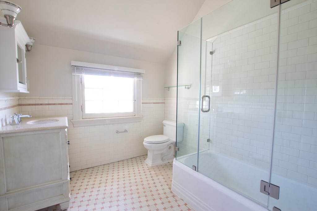 a white bathroom with a shower toilet and sink