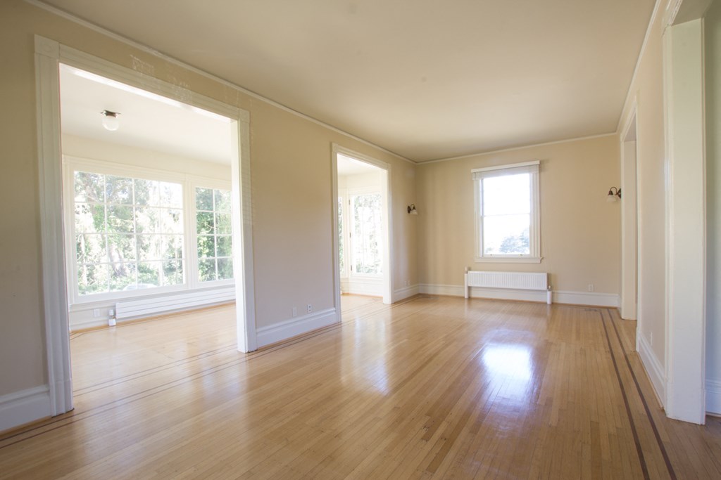 an empty living room with wood floors and large windows
