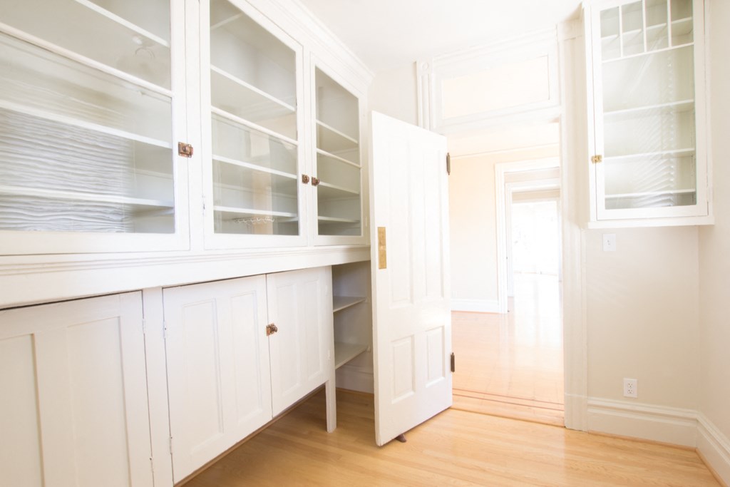 a white kitchen with white cabinets and a wood floor