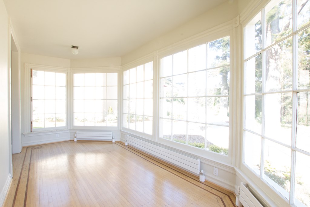 a sun room with a wooden floor and large windows