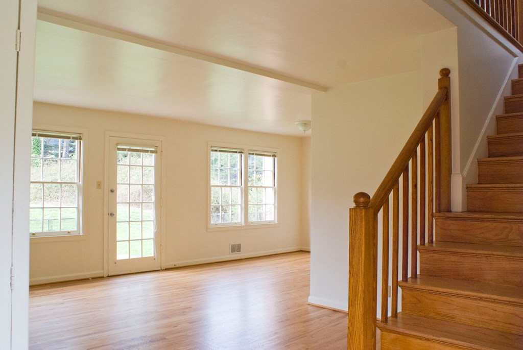 an empty living room with wood floors and a staircase