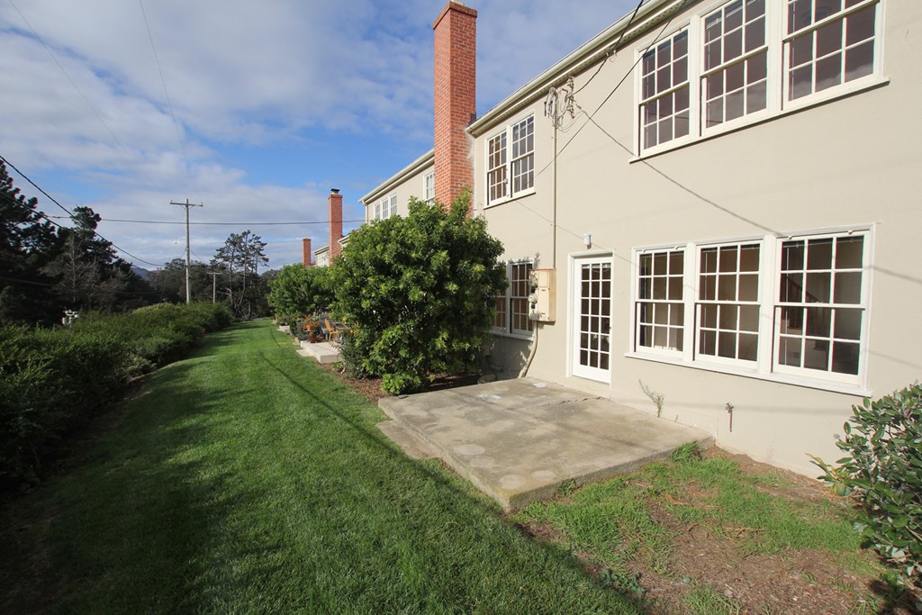 the side of a house with a concrete walkway next to it