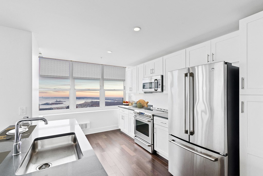 an all white kitchen with stainless steel appliances and a large window