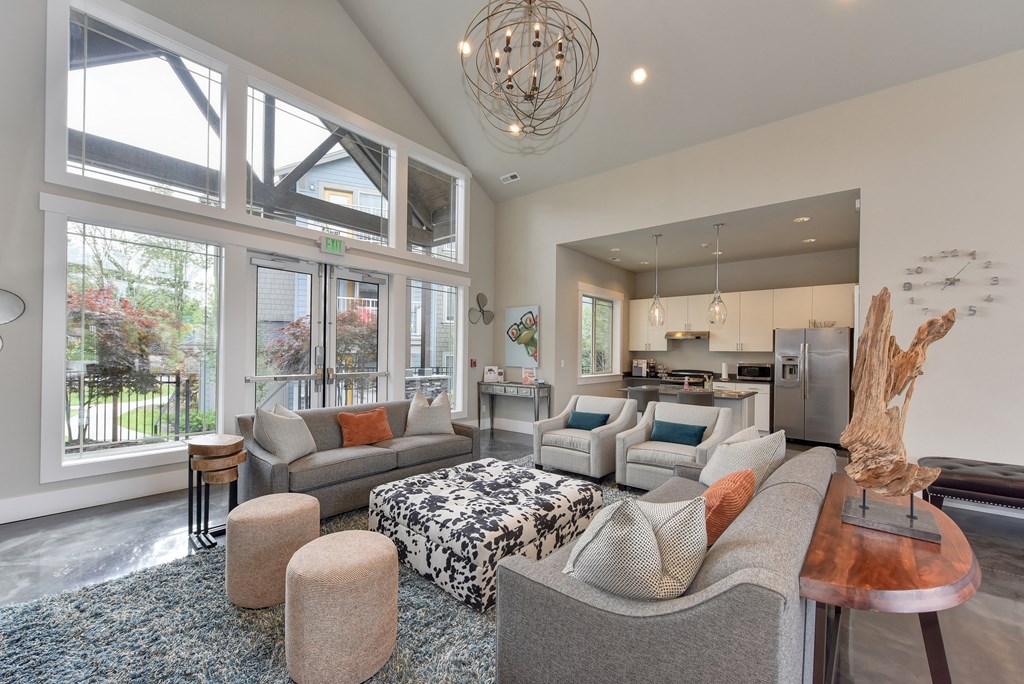 Clubhouse Room with Gray Sofa and Chairs, Full View Glass Doors, View of Kitchen Interior, Carpet and Wood Inspired floor