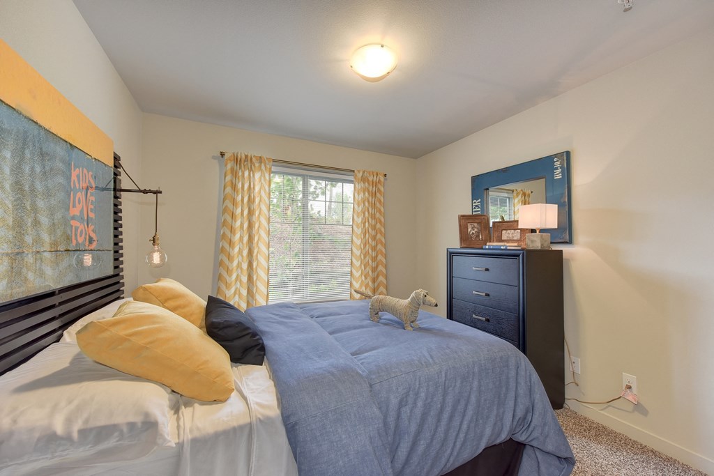 Master Bedroom with Kings Sized Mattress with Blue Comforter, Woven Dog, Black Dresser, Carpet and