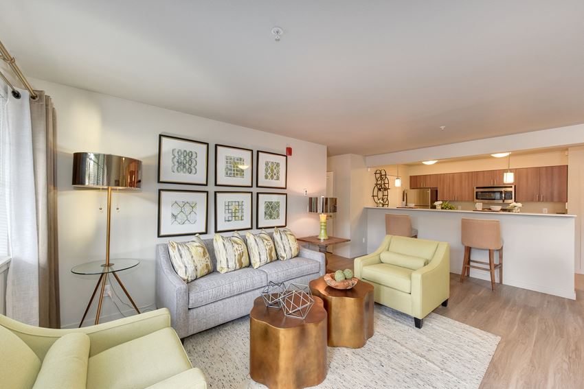Model Living Room with Couch, View of Kitchen, White Sofa, Hardwood Inspired Floor, Lime Chairs, and Lamp on Glass Table - Photo Gallery