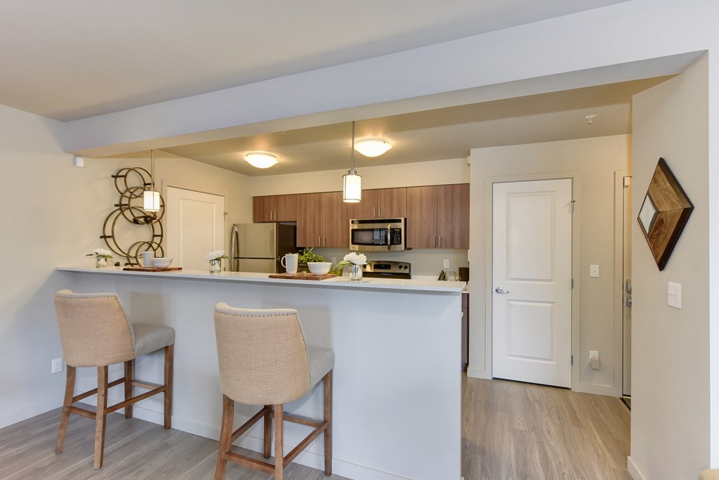 Model Kitchen with Counter,Stools, Hardwood Inspired Floor, Ceiling Lights, and Fridge/Freezer