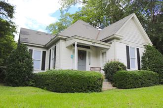a white house with a blue door and green grass and trees