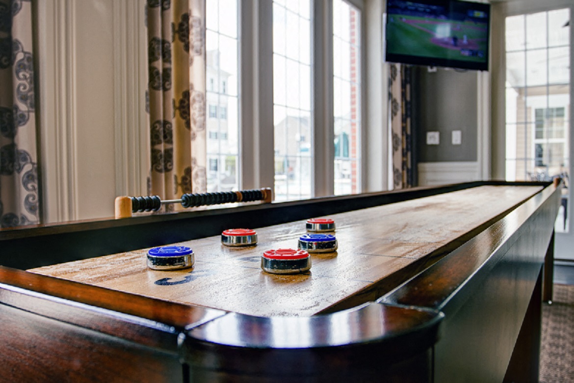 a shuffleboard table in a room with windows and a tv