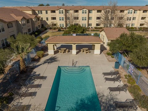 an aerial view of a pool and patio with an apartment building in the background