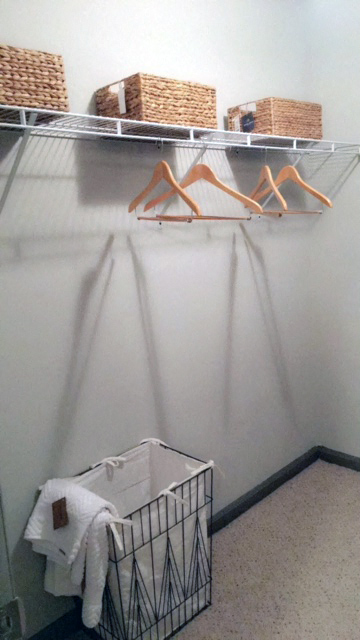 a laundry room with a basket and hangers on the wall