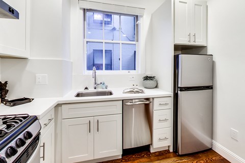 A kitchen with white cabinets and a stainless steel refrigerator.